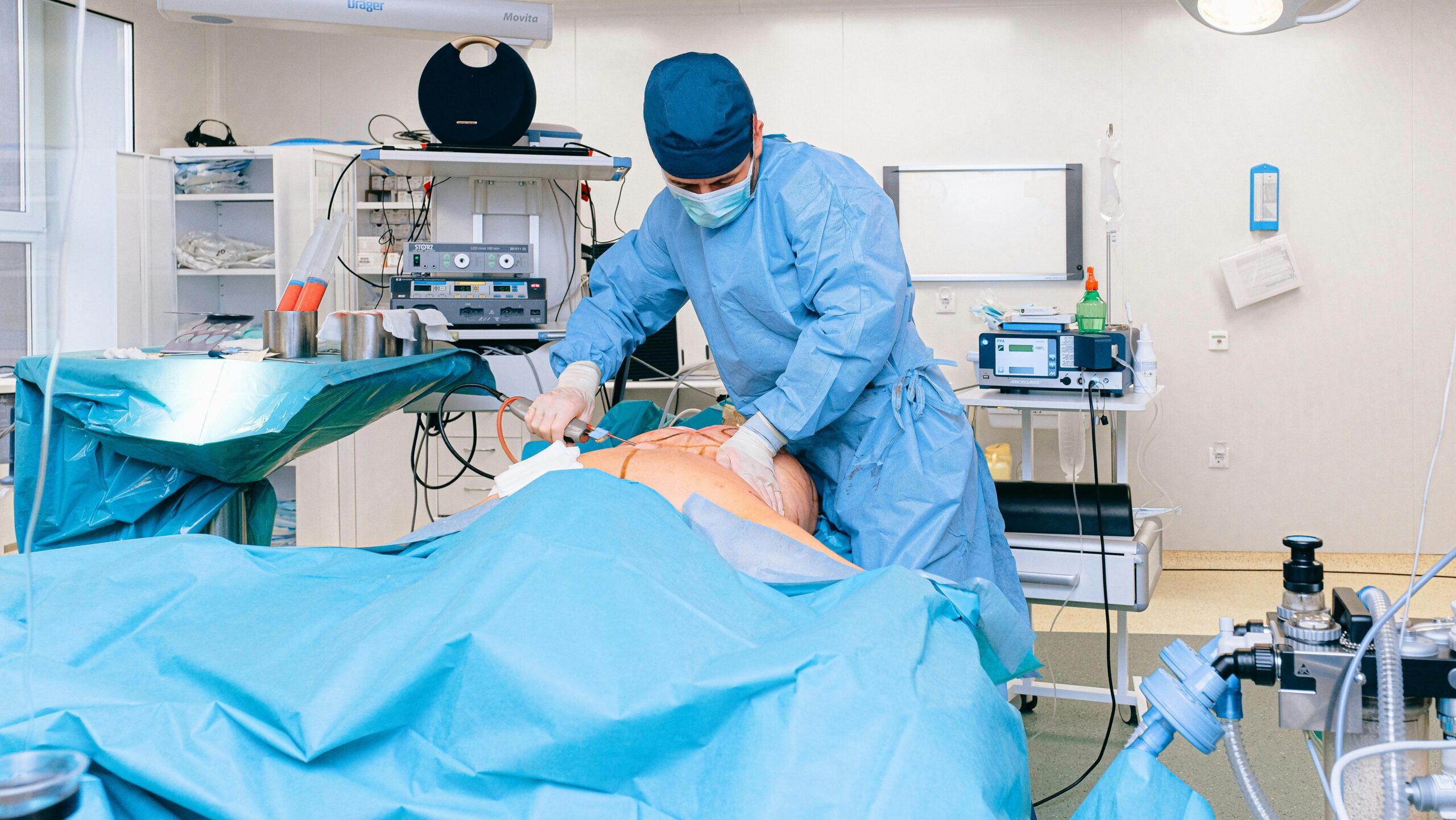 A surgeon in scrubs operates in a sterile hospital environment using advanced medical equipment.