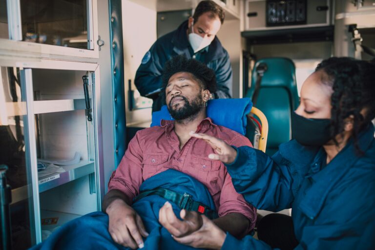 Paramedics provide urgent care to an injured man inside an ambulance.